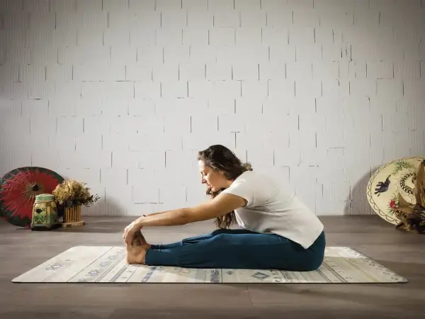 Mujer en postura de yoga Paschimottanasana, explorando el hatha significado de la calma y la conexión.