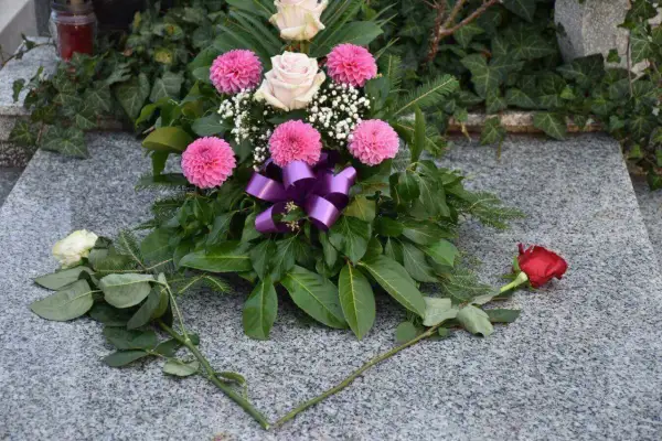 Piękna wiązanka z różowych i białych róż, ozdobiona fioletową wstążką. Dodatki do wiązanek na cmentarz, które dodają uroku i pamięci.