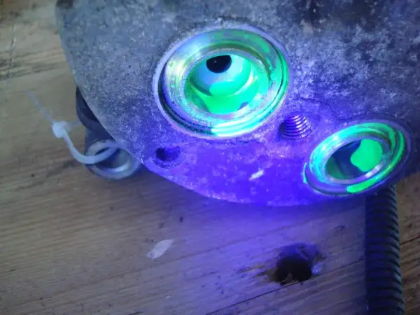 Détection de fuite climatisation voiture : le traceur fluorescent vert révèle une infiltration dans le compresseur.