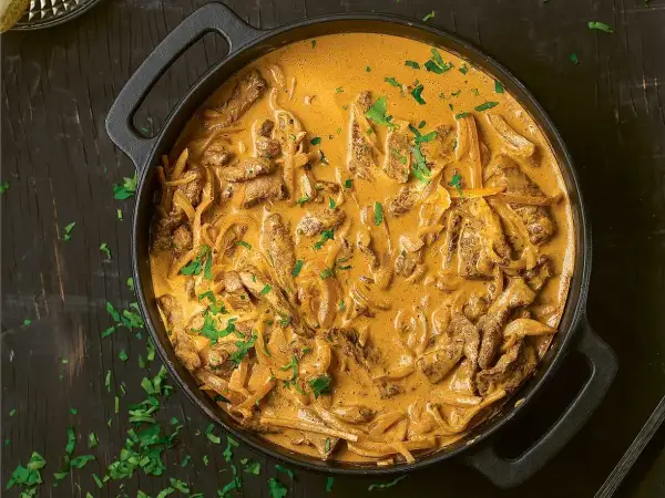 En krämig biff stroganoff i en gjutjärnspanna, toppad med färsk persilja.
