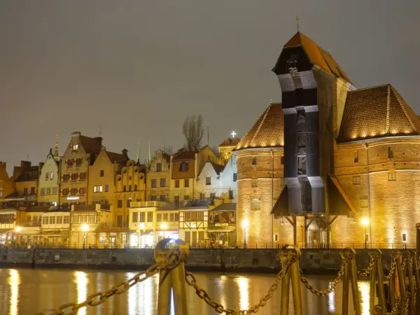 Gdańsk nocą, z Żurawiem i kamienicami odbijającymi się w wodzie.