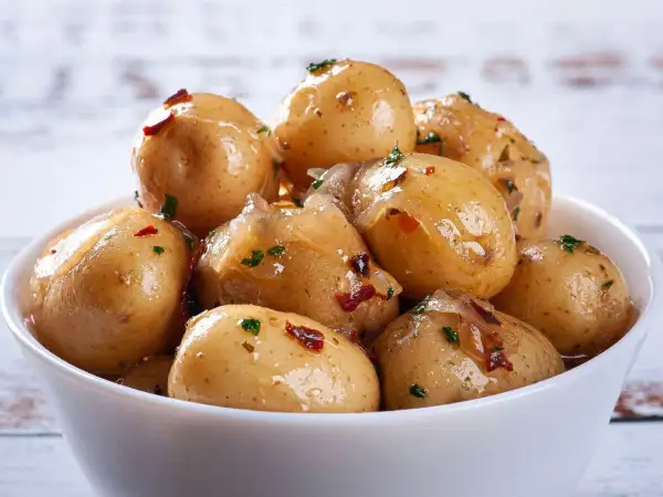 Miseczka pełna pysznych, błyszczących kiszonych ziemniaków z dodatkiem ziół i papryczki chili. Idealne jako dodatek do obiadu.
