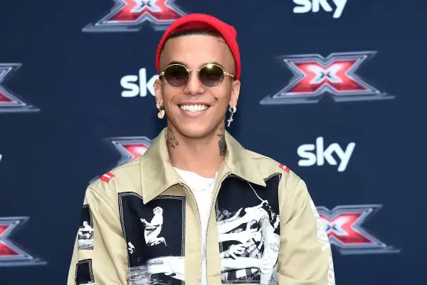 Artista con cappellino rosso e occhiali da sole, pronto a cantare le canzoni trap più famose.
