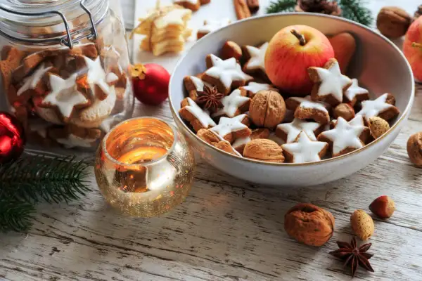 Weihnachtsplätzchen, Nüsse und ein Apfel in einer Schale, dazu eine Kerze – das ist die Bedeutung von Weihnachten: Gemütlichkeit und Genuss.