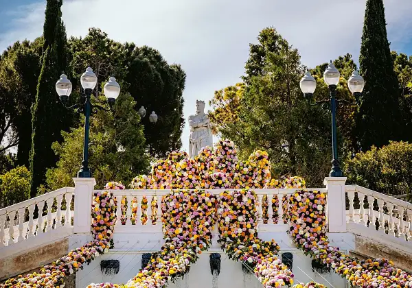 Escaleras adornadas con miles de flores vibrantes, donde zgz florece en un espectáculo de color. Una estatua real preside la escena.