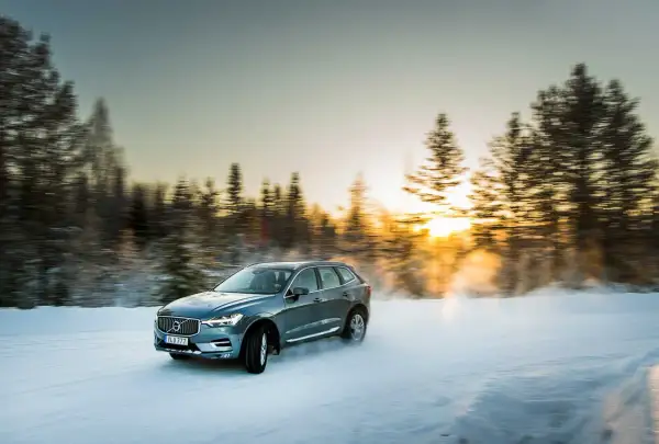 Volvo XC60 med d4 motor kör på snöig väg i solnedgången.