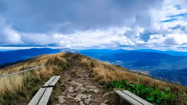 Kamienista ścieżka prowadzi na szczyt, skąd roztacza się widok na Bieszczady. W oddali widać kolejne pasma górskie.