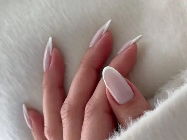 Dłonie z mlecznymi paznokciami w stylu french manicure, delikatne i eleganckie.