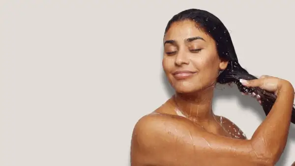 Frau mit geschlossenen Augen, die sich die nassen Haare wäscht. Sie genießt die Pflege, als würde sie ihre Haare nur mit Conditioner waschen.