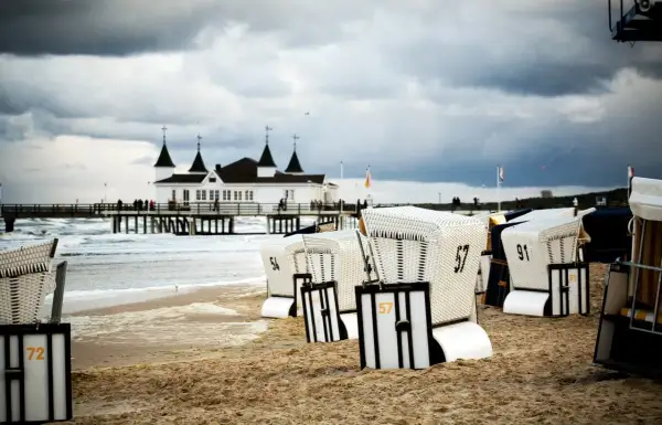 Strandkörbe am Ostseestrand mit Pier und Gebäude im Hintergrund. Perfekte ausflugsziele ostsee bei schlechtem wetter, um dem Wind zu trotzen.