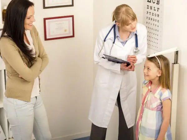 Medico misura altezza bambina, madre osserva. Valutazione del rapporto altezza peso per la crescita.