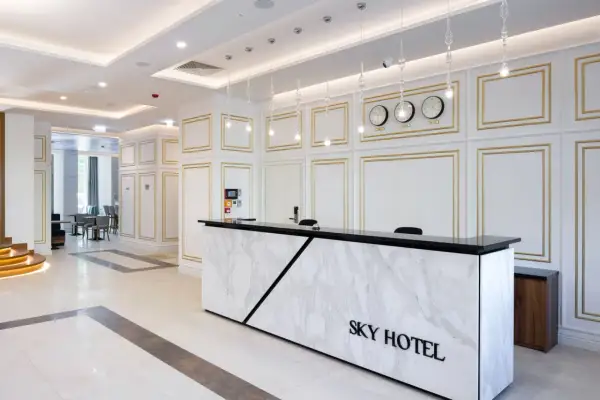 Eleganckie lobby hotelu Sky Kraków z marmurowym recepcjonistą i zegarami światowymi.