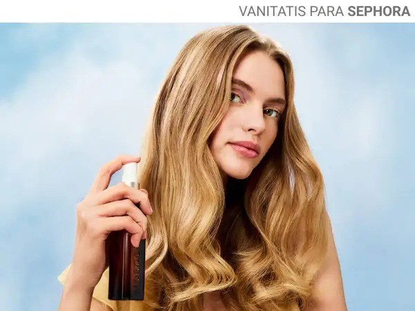 Mujer rubia aplica bruma en su pelo, logrando un brillo radiante.