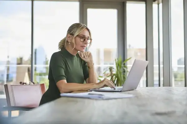 Kobieta w okularach pracuje na laptopie, szukając informacji, jak założyć konto w BIK.