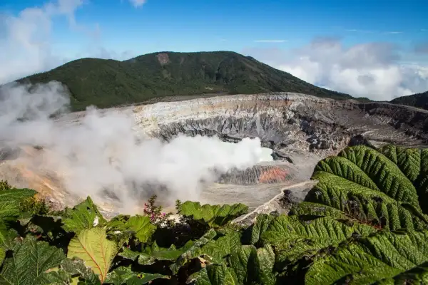 Vulkanen Poás i Costa Rica med sin turkosa sjö och ångande krater, omgiven av frodig grönska.