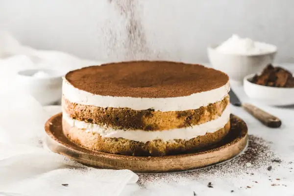 Ein köstlicher Tiramisu-Kuchen wird mit Kakaopulver bestäubt.