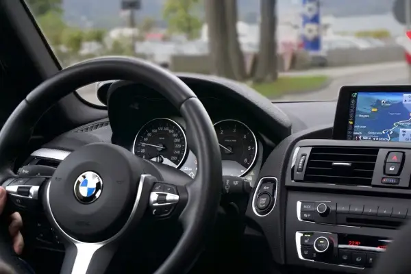 Wnętrze BMW z kierowcą, który zdaje egzamin kontrolny po utracie prawa jazdy za punkty. Nawigacja pokazuje trasę.