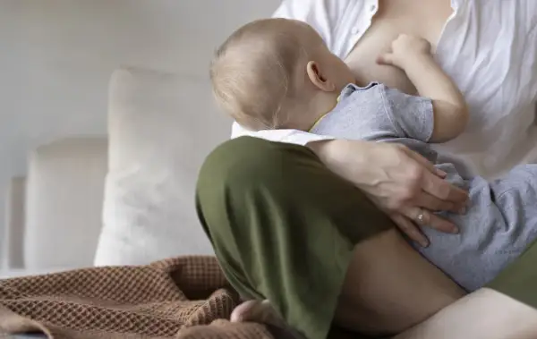 Ciepły dzień karmienia piersią. Mama tuli dziecko, które pije mleko.