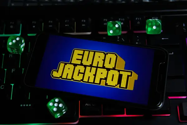 Zielone kostki do gry i ekran telefonu z napisem "EURO JACKPOT" na podświetlanej klawiaturze. Czy to przypadek, dlaczego te same euroliczby wypadły w dwóch losowaniach pod rząd?