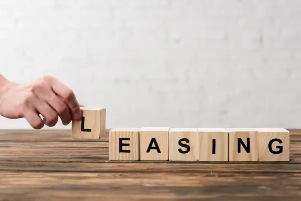 Dłoń układa kostkę z literą "L", tworząc słowo "LEASING". Zastanawiasz się, czy leasing się opłaca?