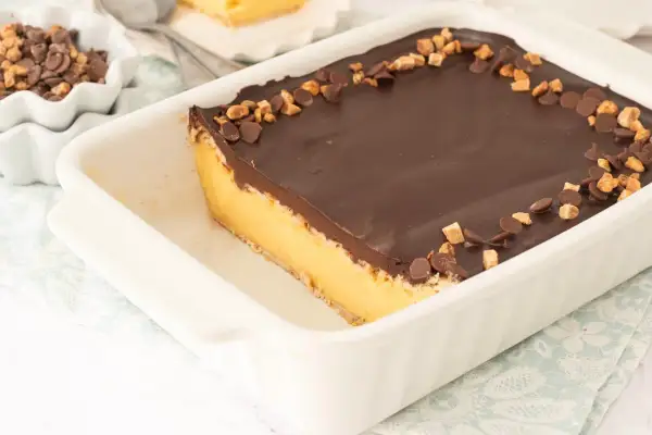 Tarta de natillas y galletas con cobertura de chocolate y trocitos de galleta y chocolate.