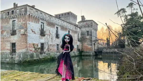La Dama Bianca leggenda: una bambola gotica posa davanti a un castello antico con un fossato.