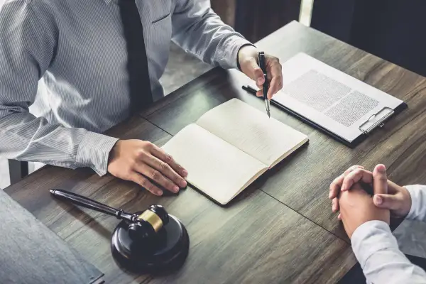Avvocato e cliente discutono, con un martelletto da giudice e un quaderno aperto. Il ctu significato è fondamentale per la giustizia.
