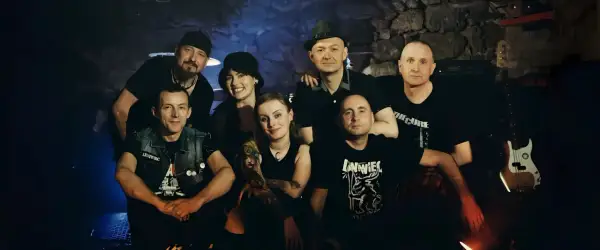 Grupa przyjaciół, zespół Leniwiec, pozuje do zdjęcia w mrocznym wnętrzu.