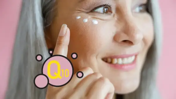 Mujer sonríe mientras se aplica crema en el contorno de ojos. El Q10 es un ingrediente clave para el cuidado de la piel.
