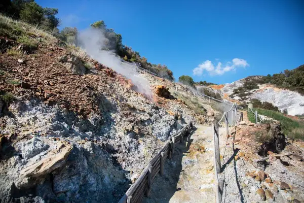 Sentiero nel **parco delle Biancane** con fumarole fumanti e rocce colorate.