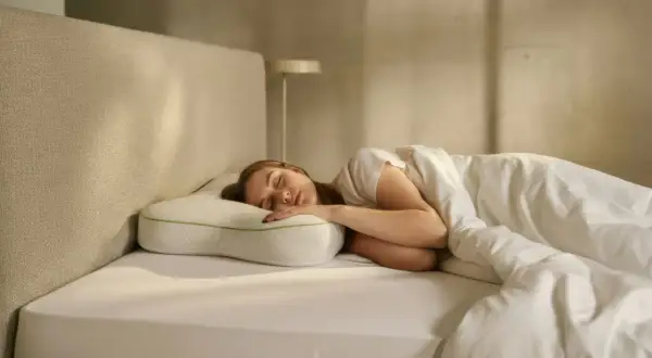 Junge Frau schläft tief und fest auf einem ergonomischen Kissen. Ein Zeichen für erholsamen Schlaf, vielleicht dank eines guten hausmittel besser schlafen.
