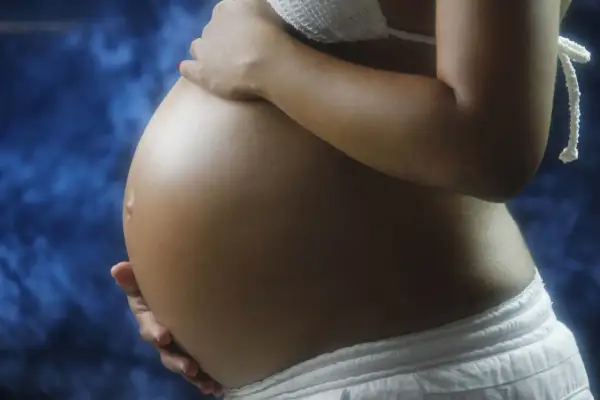 Gravid mage med händer som varsamt vilar på den. Kanske är det latensfas flera dygn, en väntan fylld av hopp.