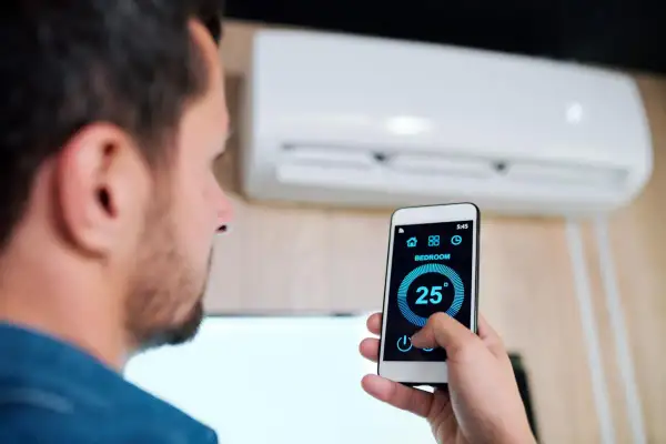 Uomo controlla condizionatore Mitsubishi con smartphone, mostrando come collegare condizionatore Mitsubishi wifi per gestire la temperatura da remoto.