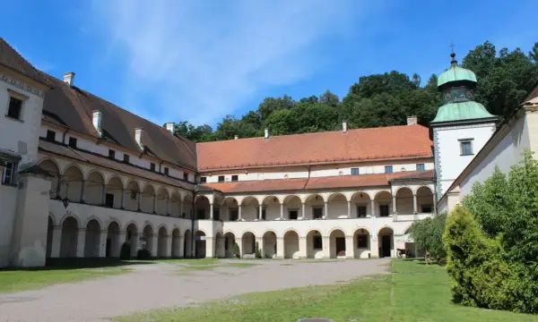 Dziedziniec zamku w Suchej Beskidzkiej z arkadowymi krużgankami i zieloną wieżą.