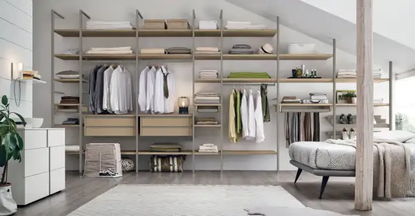 Una cabina armadio mansarda bassa, con scaffali in legno e metallo, ospita abiti ordinati e accessori.