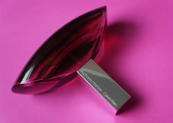 Perfumy Calvin Klein Euphoria Intense w szklanej, fioletowej butelce na różowym tle.