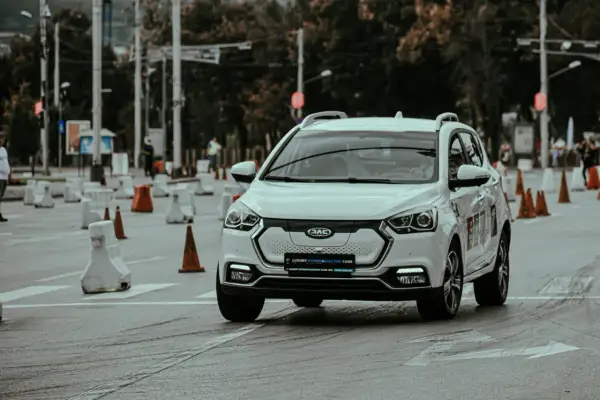 Voiture blanche lors d'un stage de sensibilisation à la sécurité routière, slalomant entre des cônes et des barrières.