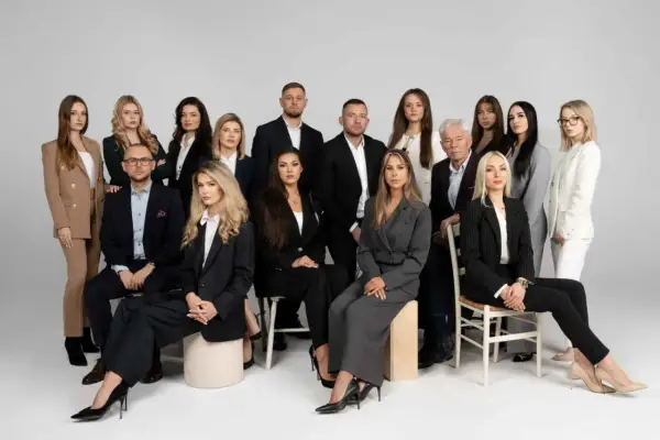 Grupa prawników w formalnych strojach pozuje do zdjęcia na jasnym tle.