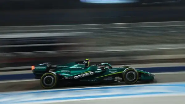Un coche Aston Martin Honda verde compite a gran velocidad en una pista nocturna, con las luces y el fondo difuminados por el movimiento.