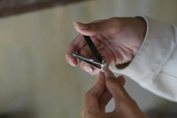 Une main utilise un coupe-ongles pour couper un ongle homme.