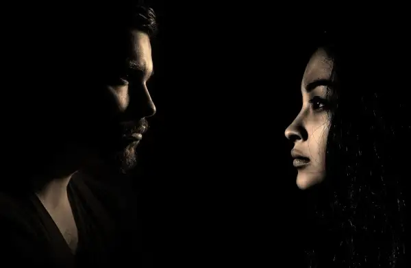 Profili di un uomo e una donna si fronteggiano nel buio, un'immagine che evoca il silenzio dopo la fine di una storia.