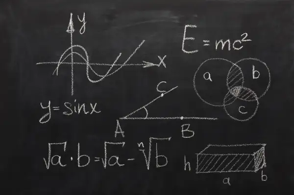 Rysunki matematyczne na tablicy: wykres funkcji sinus, wzory, diagramy Venna, bryła.