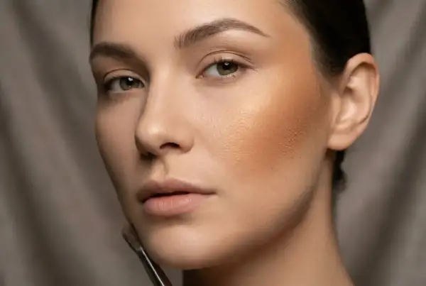 Kobieta z pędzlem do makijażu aplikuje bronzer, tworząc ciepły, promienny wygląd.