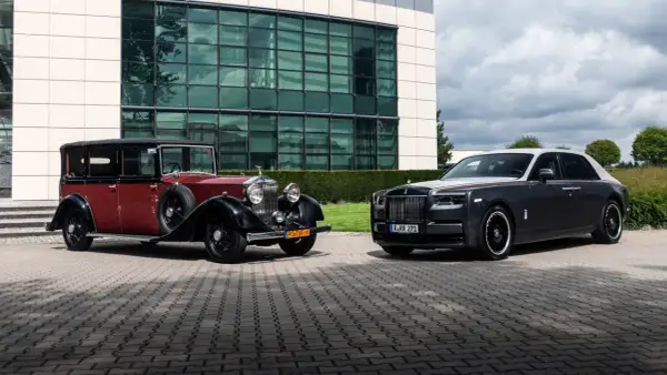 Dwa Rolls-Royce'y Phantom: zabytkowy czerwono-czarny i nowoczesny grafitowo-biały, stojące przed budynkiem.