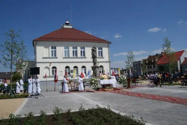 Uroczystość religijna na rynku w **Borku Wielkopolskim**. Kapłan odprawia mszę, towarzyszą mu ministranci i wierni.