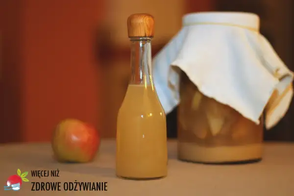 Butelka z octem jabłkowym, obok jabłko i słoik z fermentującymi jabłkami. Czy ocet jabłkowy zawiera alkohol?