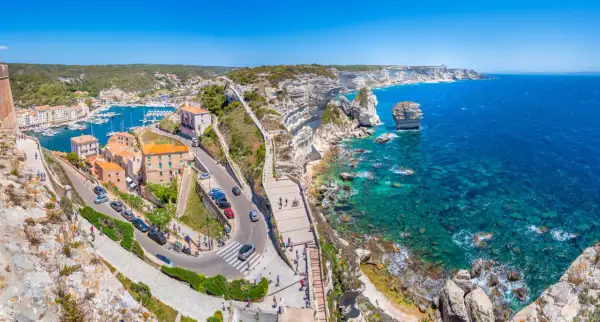 Vue panoramique de Bonifacio, Corse. La ville perchée sur les falaises blanches surplombe un port animé et une mer turquoise. Idéal pour visiter Bonifacio.