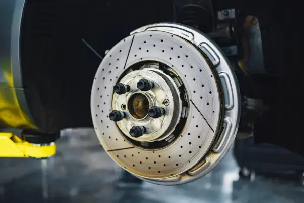 Disque de frein perforé et ventilé, prêt à arrêter la voiture. Ce frein qui siffle pourrait indiquer un besoin de maintenance.