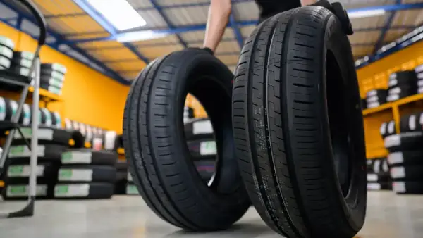 Deux pneus de voiture neufs, une sous-marque Michelin, sont présentés dans un entrepôt rempli de pneus.