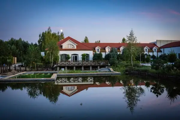 Eleganckie spa koło Warszawy z basenem i stawem odbijającym budynek. Idealne miejsce na relaks.